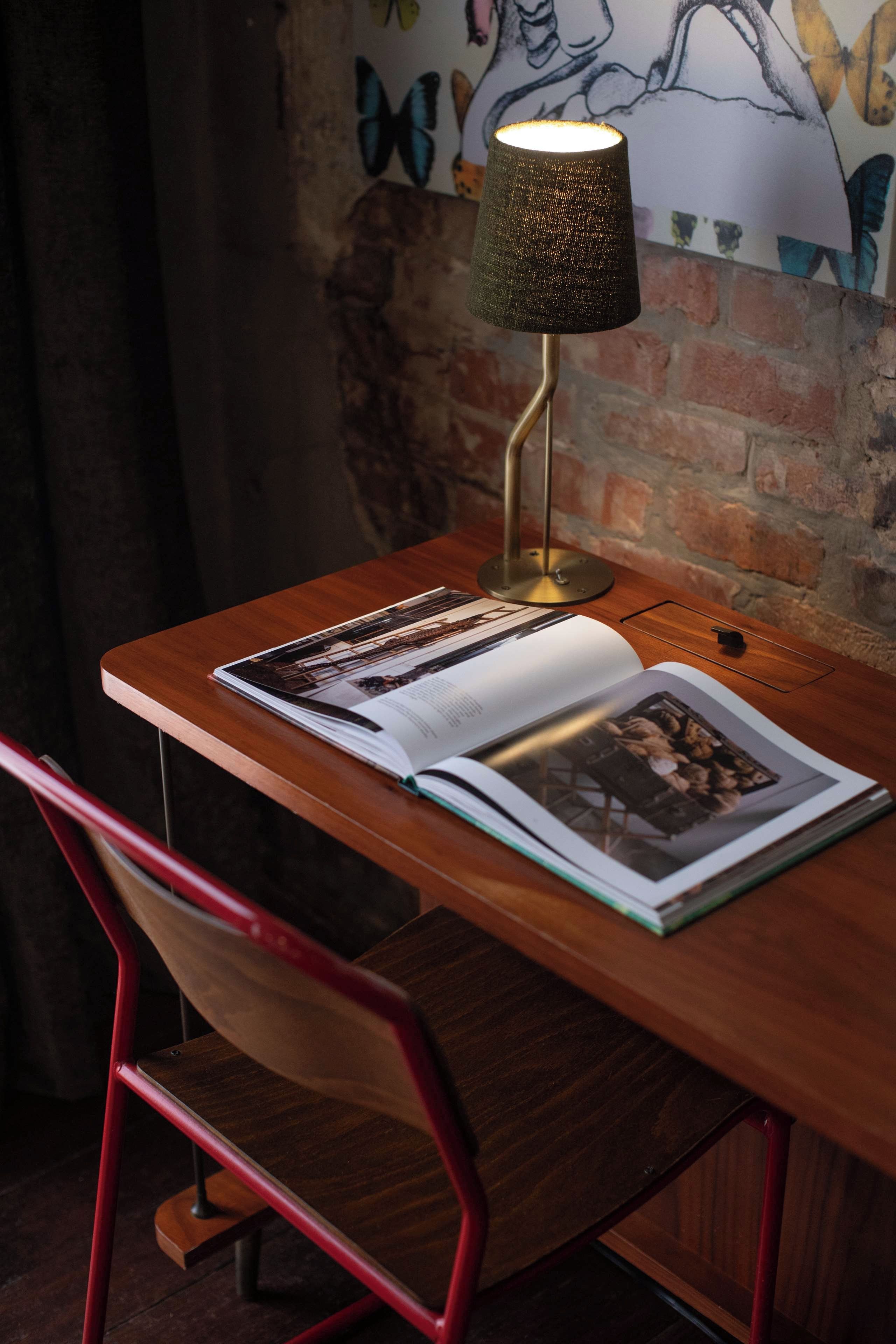 A wooden desk with a lamp, a book, and a chair.