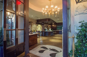 A hotel lobby with a reception desk, a bar area, and a chandelier.