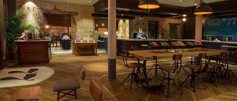 A restaurant with a rustic interior, featuring exposed brick walls, wooden flooring, and a variety of seating arrangements including tables and chairs.