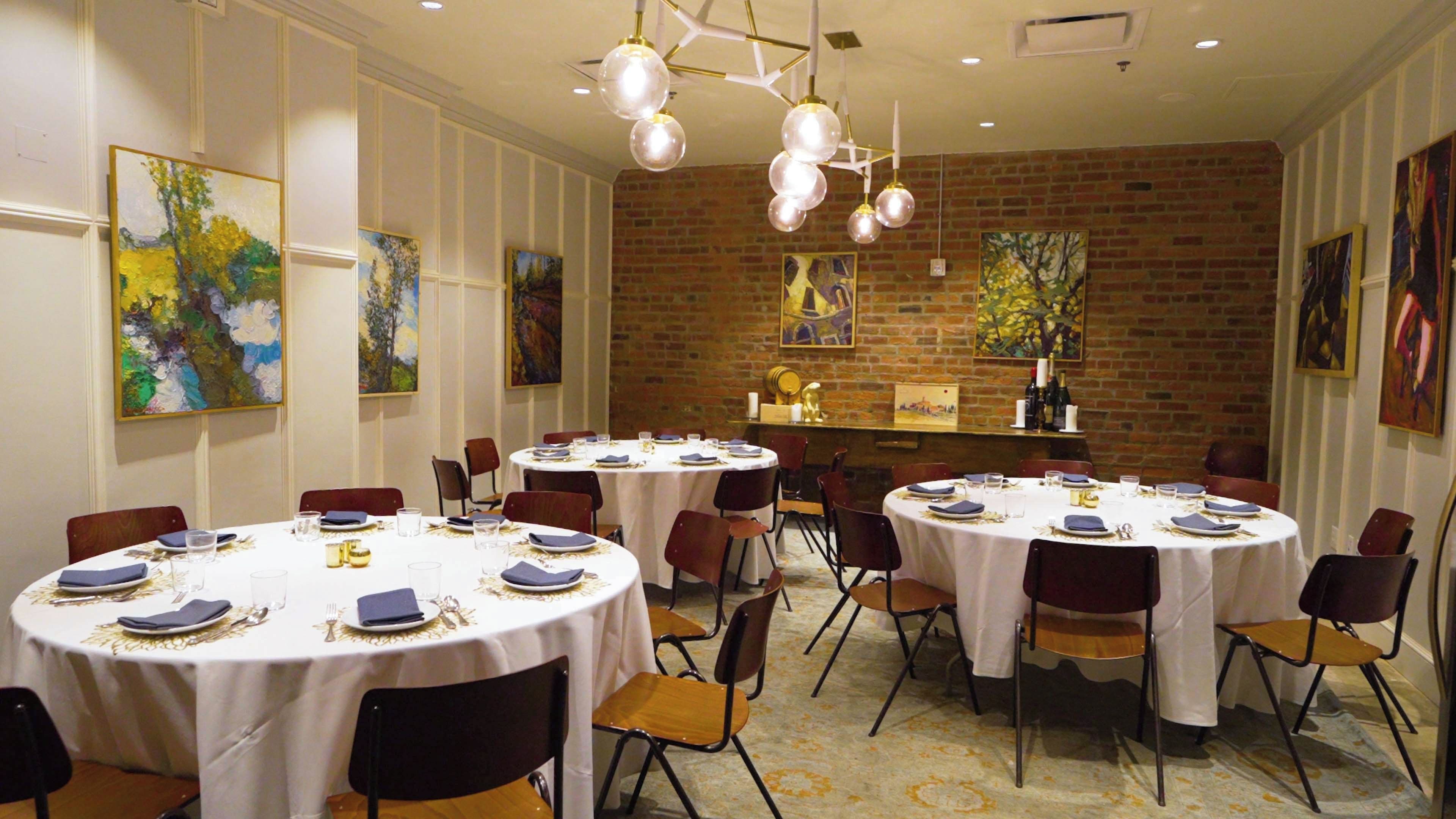 Un espace repas avec des tables rondes, des chaises et des œuvres d’art accrochées aux murs.