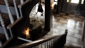 Portaat, joiden lattia on ruutukuviollinen, sohva, jossa on koristetyyny, ja lamppu.