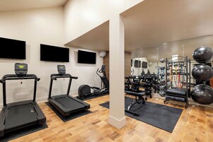 Un gimnasio moderno con cintas de correr, elípticas y equipo de levantamiento de pesas.