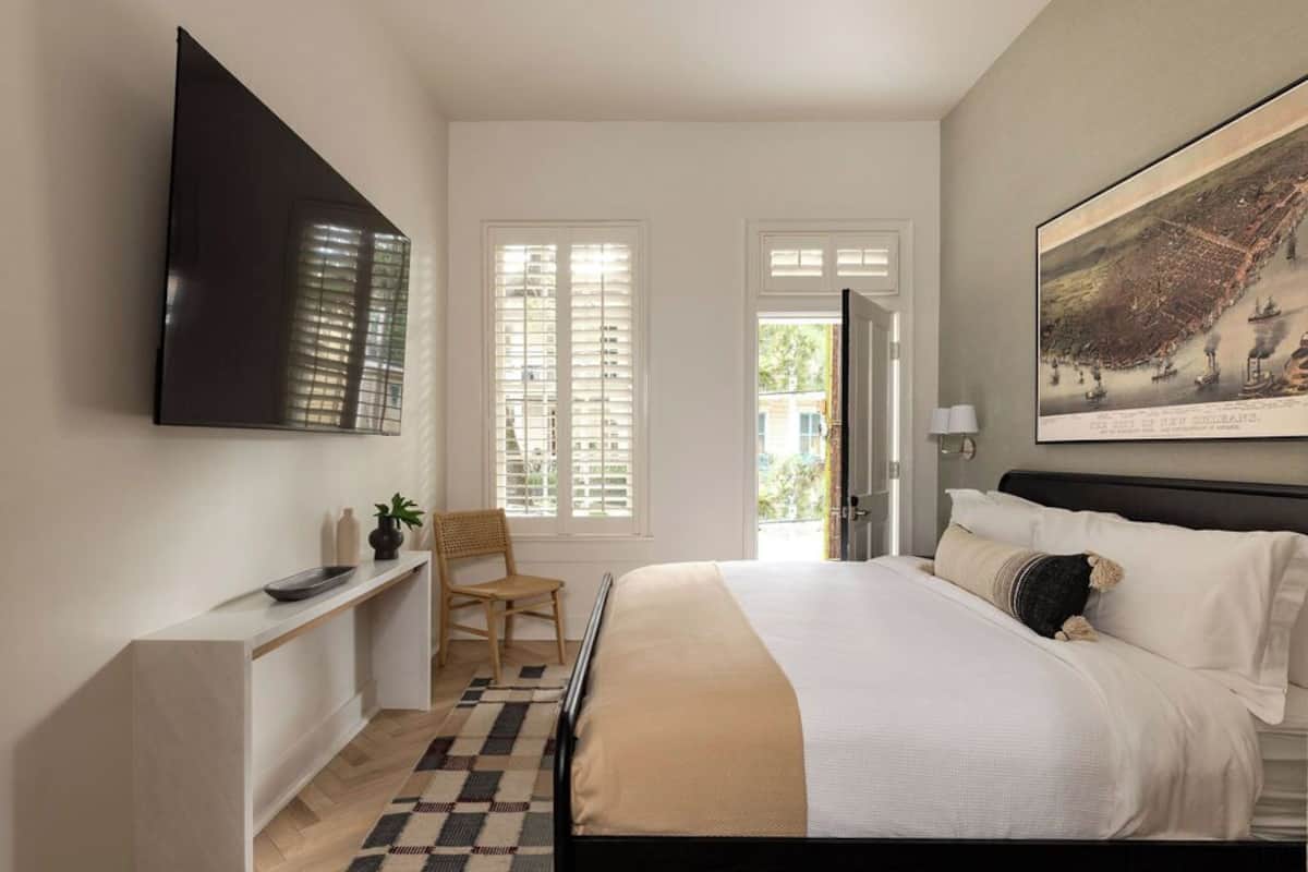 Ein Schlafzimmer mit Bett, Schreibtisch, Stuhl, Fernseher und einem Bild an der Wand.