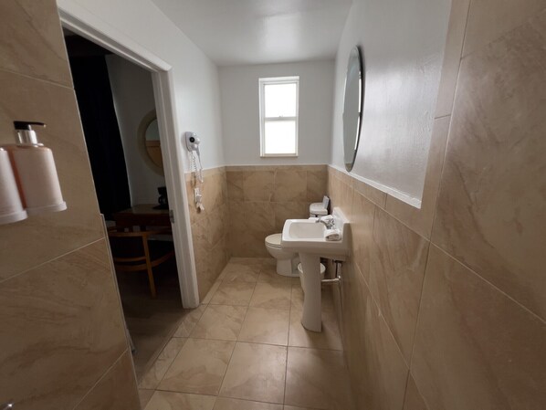 Un baño estrecho con inodoro, lavamanos y una ventana pequeña.