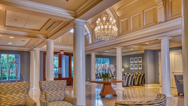 A spacious lobby with high ceilings, a chandelier, and patterned furniture.