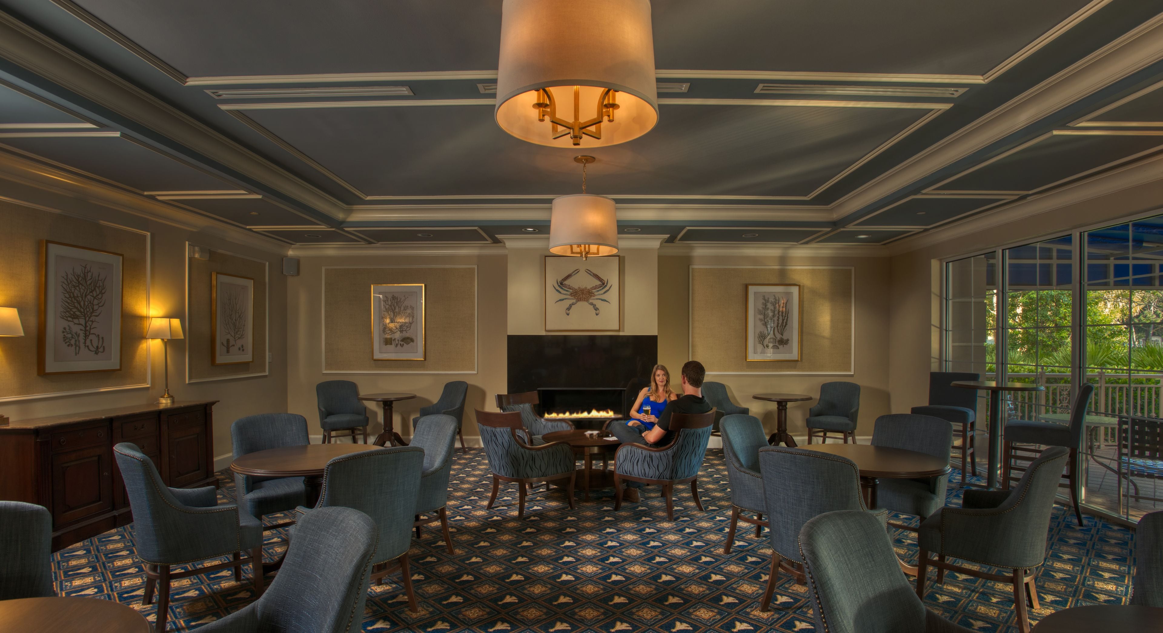 A spacious room with a fireplace, comfortable seating, and large windows.