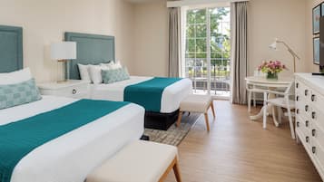 Habitación de hotel con dos camas, una mesita con lámpara, una silla y un aparador.