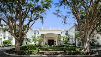 Classic hotel with a central entrance, flanked by two large trees, and a balcony above.