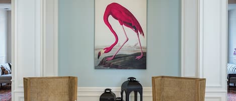 Un hall con dos sillones de mimbre, una araña, un cuadro de flamenco y una chimenea.