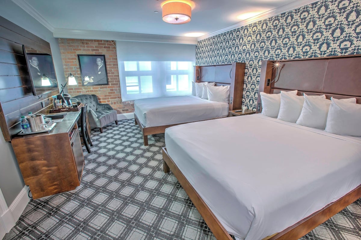 Une chambre d’hôtel avec deux lits, un bureau et une télévision.