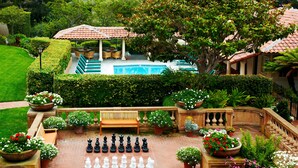 Un jardín con un tablero de ajedrez, una piscina y un pabellón.