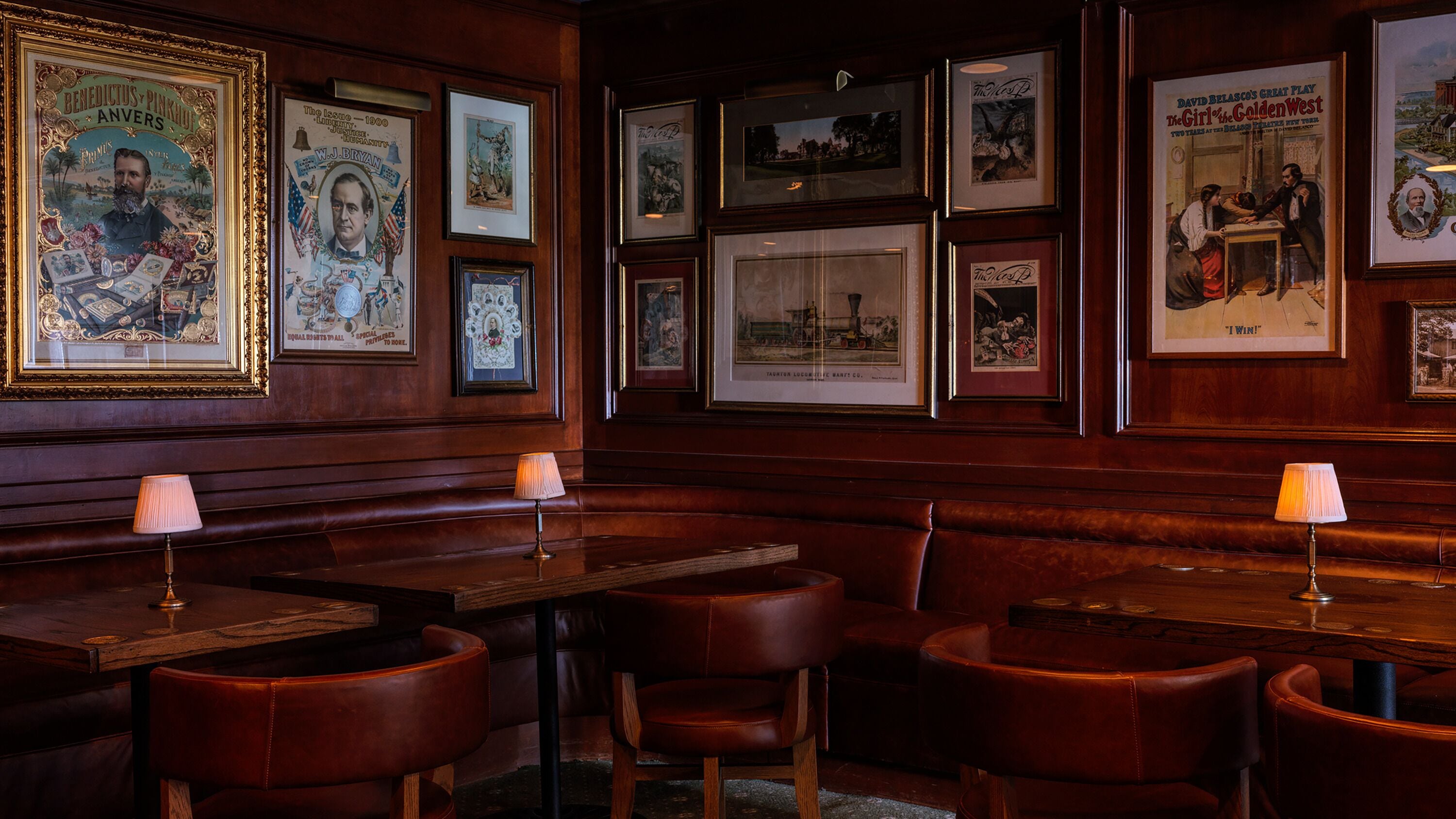 Um restaurante com lambris de madeira, assentos em couro e pôsteres emoldurados nas paredes.