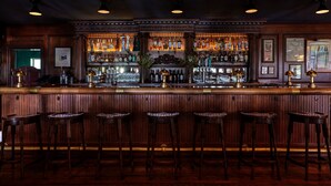 A bar with wooden bar stools and a variety of liquor bottles.