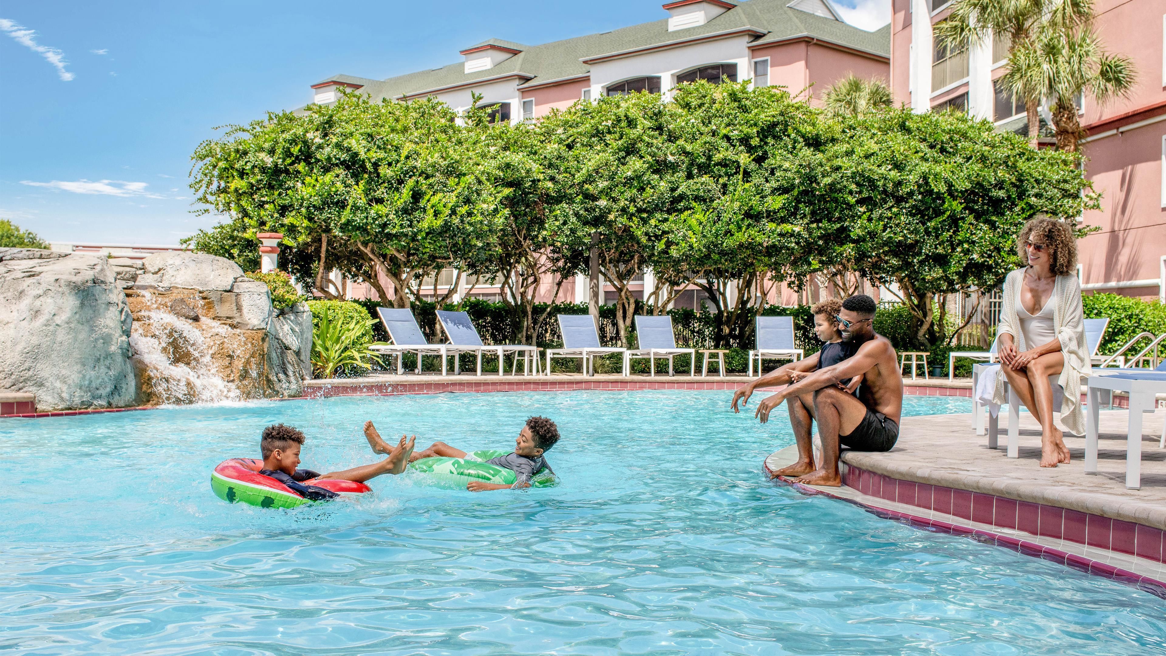 A swimming pool with lounge chairs and a waterfall feature.