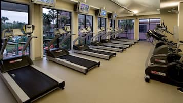Un gimnasio con varias cintas de correr, bicicletas estáticas y máquinas de cardio.
