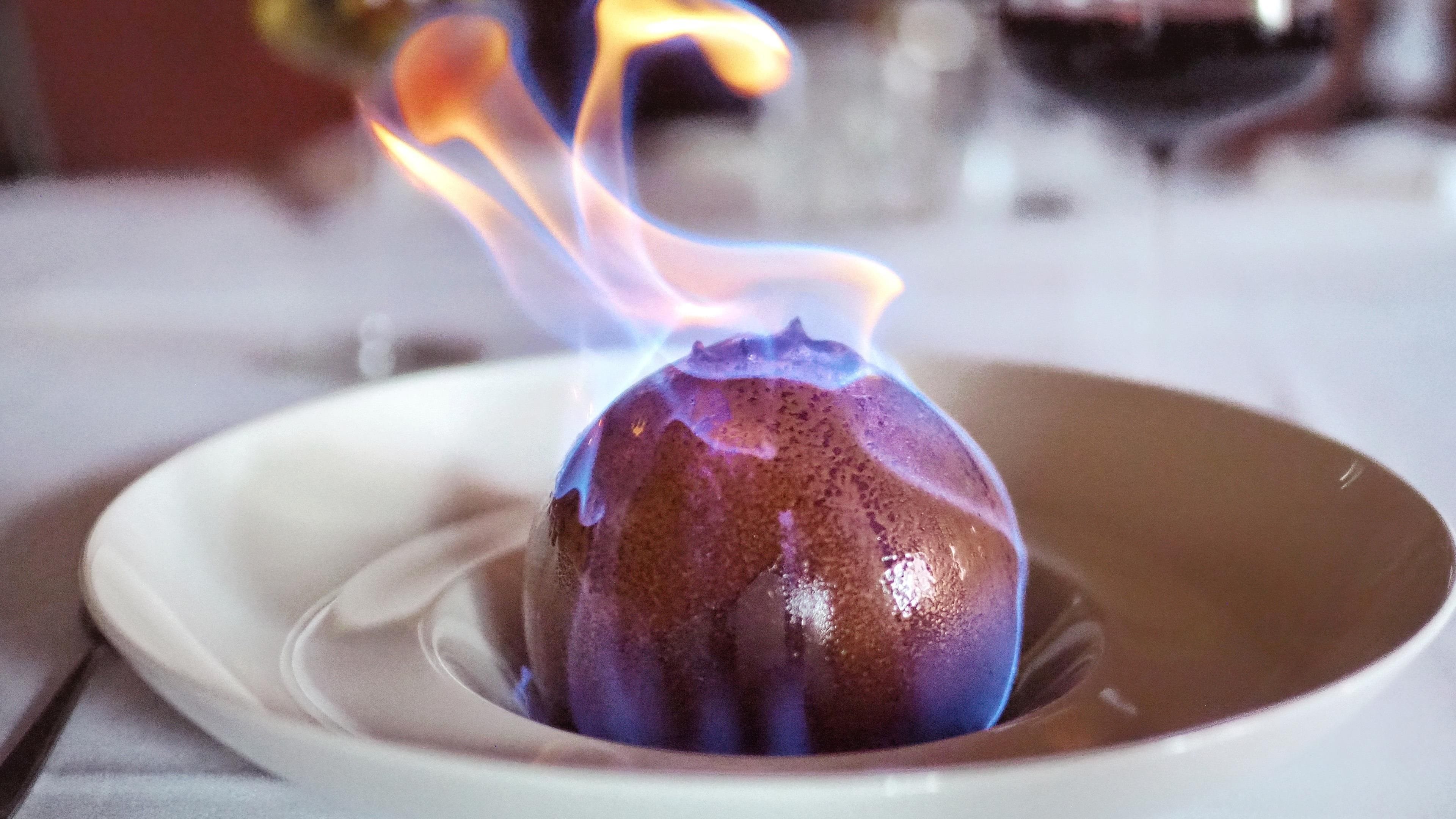 A dessert with a flame on top, served on a white plate.