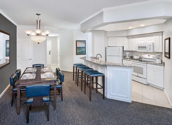 A modern kitchen with white cabinets, a granite countertop, and stainless steel appliances. - Caribe Royale Orlando, WorldHotels Elite (Orlando)