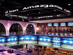 A stadium club with multiple screens displaying a stadium, bar area with bottles, and seating with a view of the screens. - Caribe Royale Orlando (Orlando)