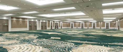 A spacious hotel room with a large carpet, recessed lighting, and a modern ceiling design.