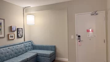 Ein Zimmer mit einem blauen, modularen Sofa, einer Tür mit Sicherheitsschloss und an der Wand befestigter Kunst.