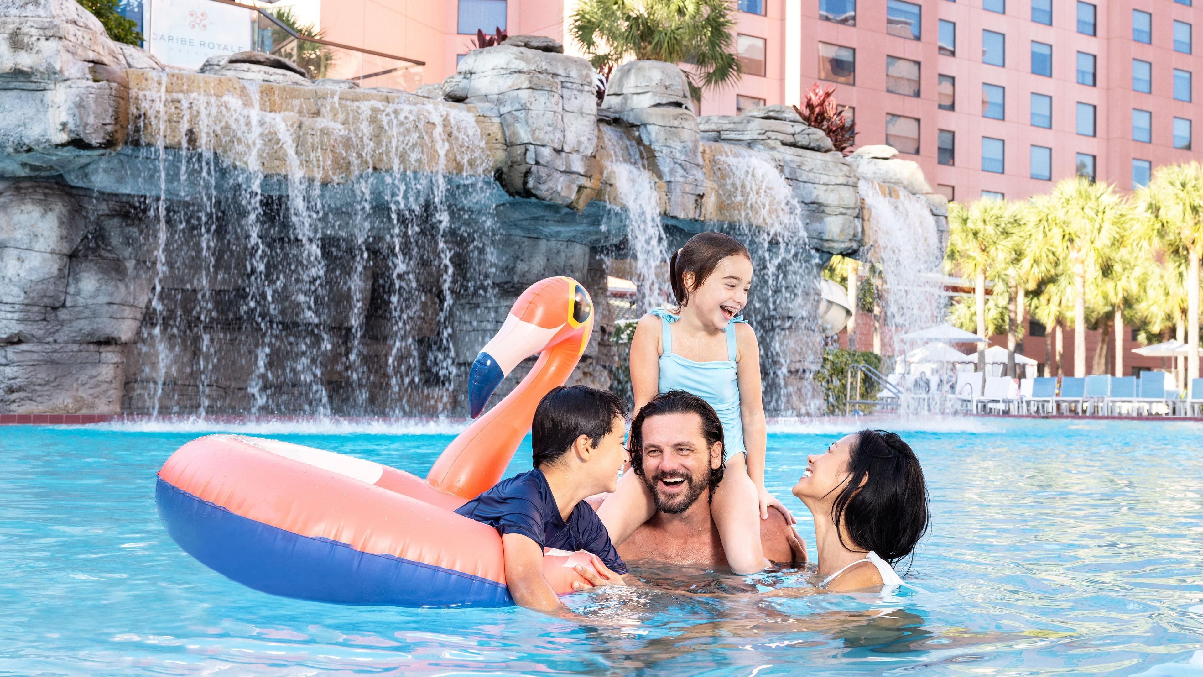 A pool with a waterfall feature and lounge chairs in the background.