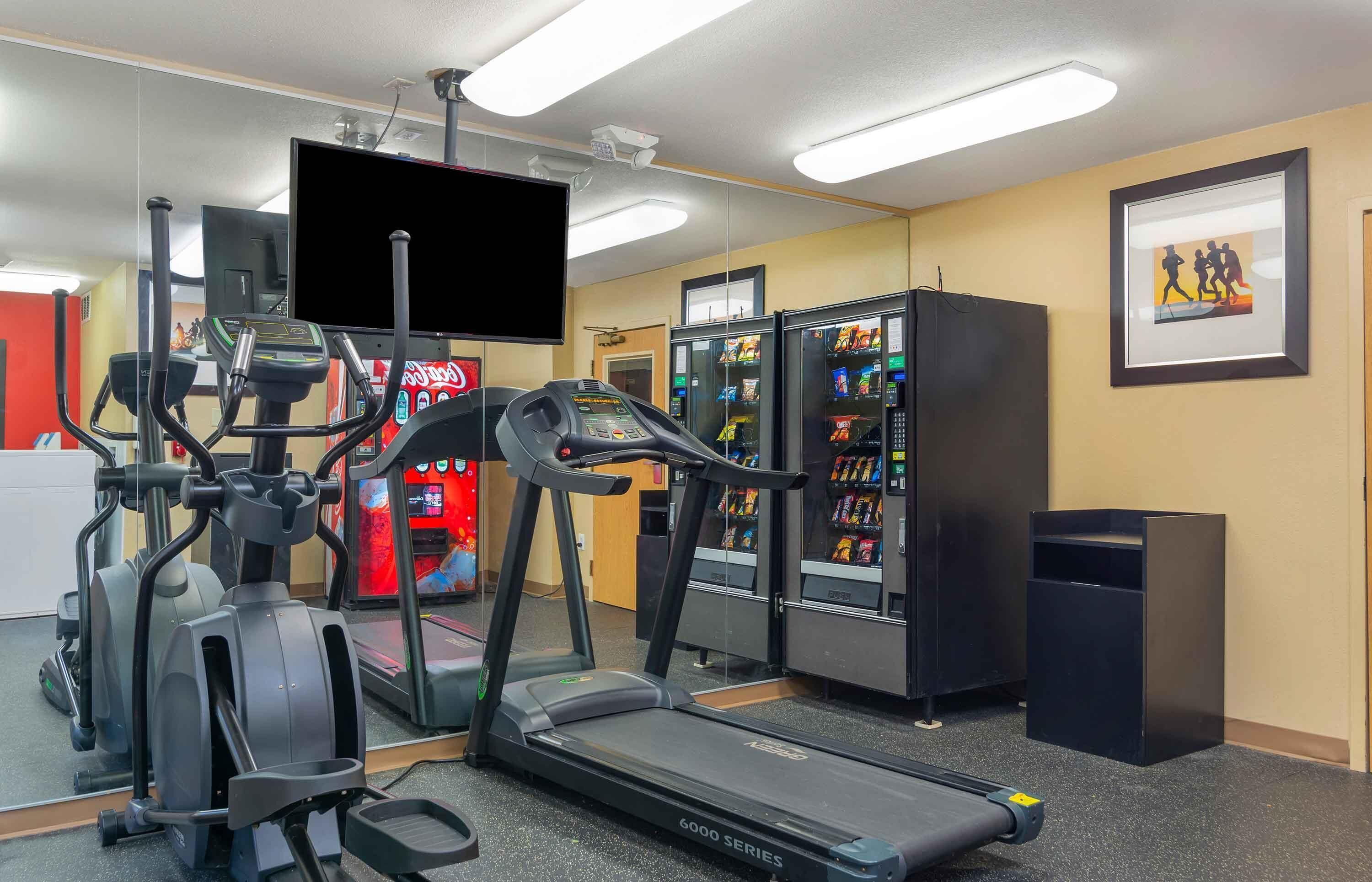 A gym with treadmills, elliptical machines, and a mirrored wall.