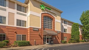 Een Stay America hotel met een hal, een groot rondboogvenster en een heldere lucht.