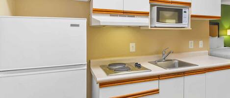 Cocina compacta con microondas, estufa y pileta.