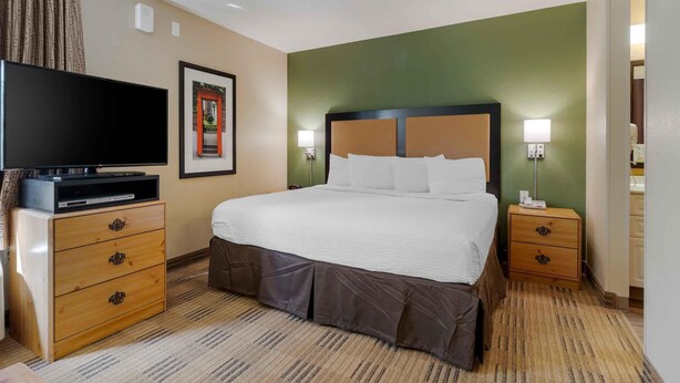 Een hotelkamer met een bed, een televisie, een nachtkastje en een aan de muur hangend schilderij.