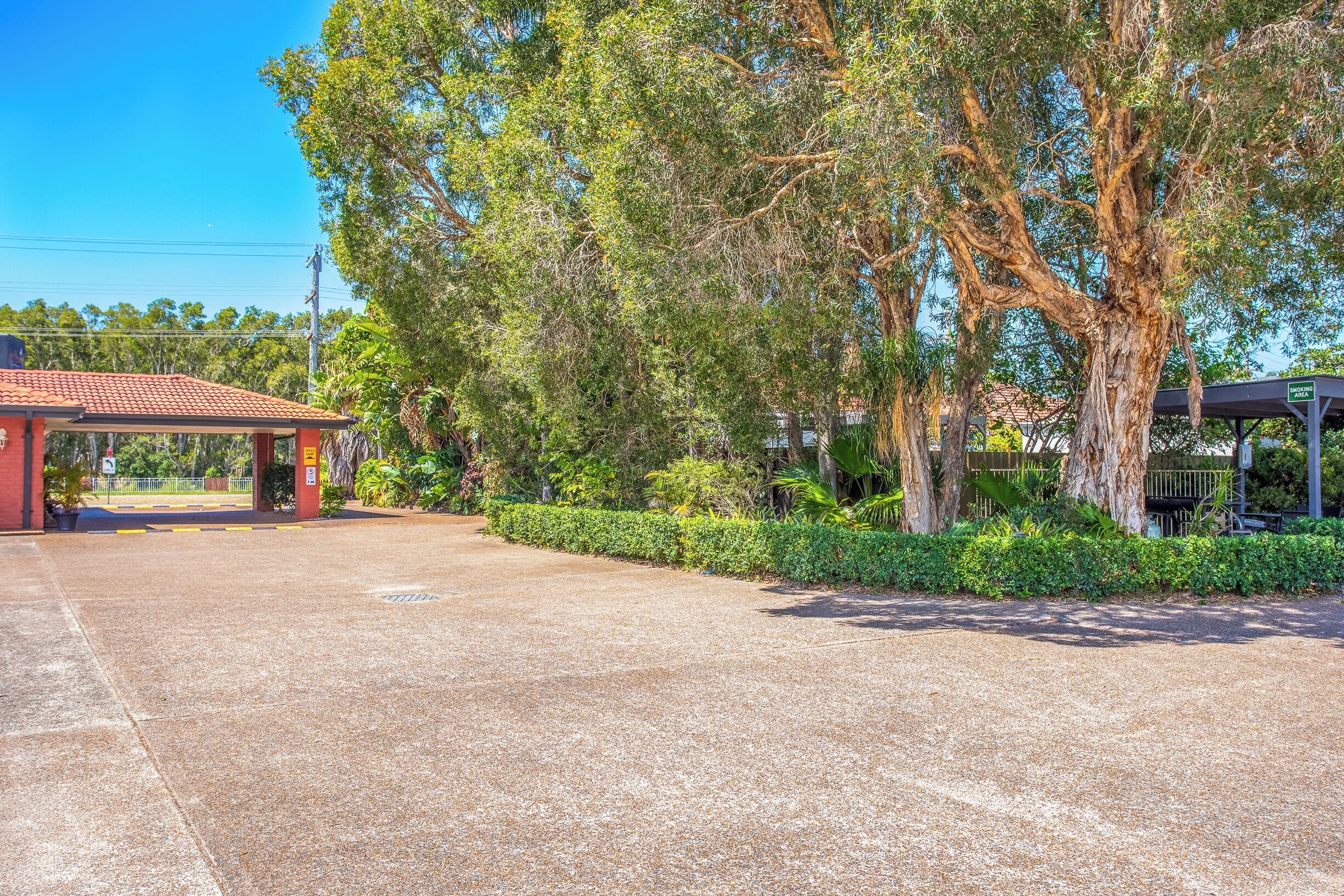 A paved parking area with a red building and a covered structure.
