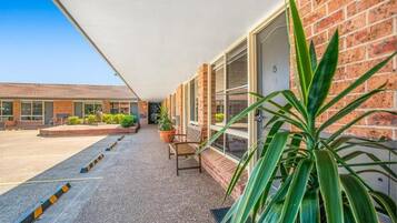 A motel with a covered walkway, potted plants, and a bench.