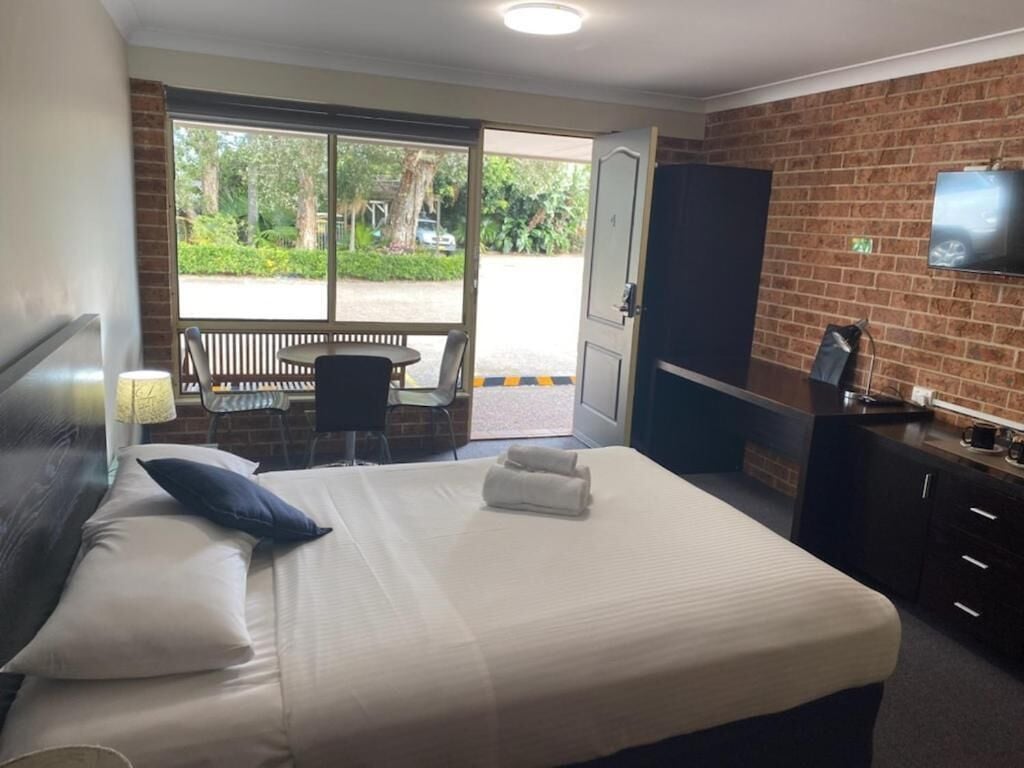 Ein Hotelzimmer mit Bett, Schreibtisch, Fernseher und Blick ins Freie.