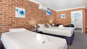 A hotel room with two beds, a brick wall, and artwork. - Lake Macquarie Motor Inn (Marks Point)