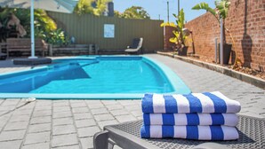 A swimming pool with lounge chairs and a stack of towels. - Lake Macquarie Motor Inn (Marks Point)