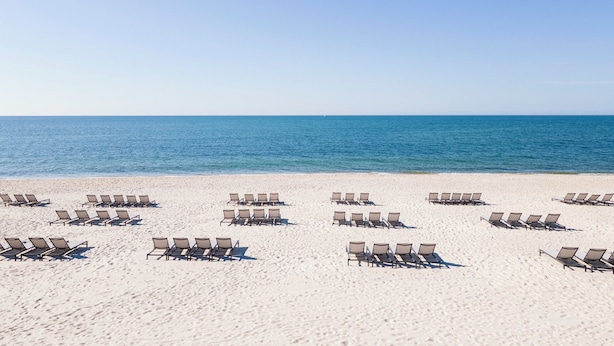 A beach with rows of sun loungers facing the ocean. - Riviera Beach Resort (South Yarmouth)