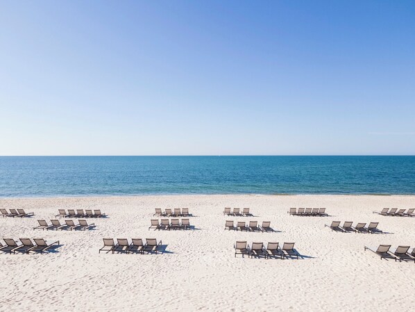 A beach with rows of sun loungers facing the ocean. - Riviera Beach Resort (South Yarmouth)