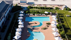 A resort with a pool area, beach chairs, and a view of the ocean. - Riviera Beach Resort (South Yarmouth)