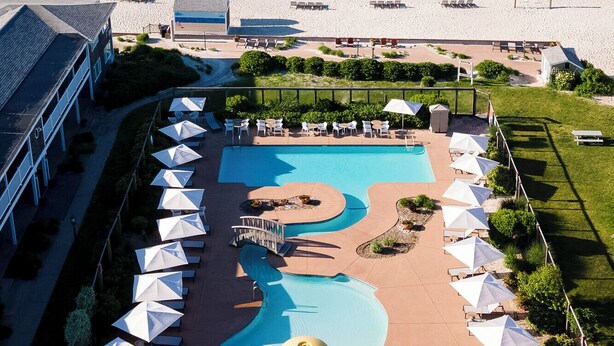 A resort with a pool area, beach chairs, and a view of the ocean. - Riviera Beach Resort (South Yarmouth)