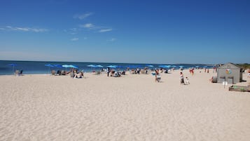 Een privéstrand, ligstoelen aan het strand, parasols, strandlakens