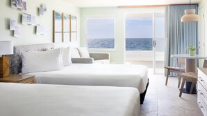 A hotel room with two beds, a desk, a chair, and a view of the sea. - Riviera Beach Resort (South Yarmouth)