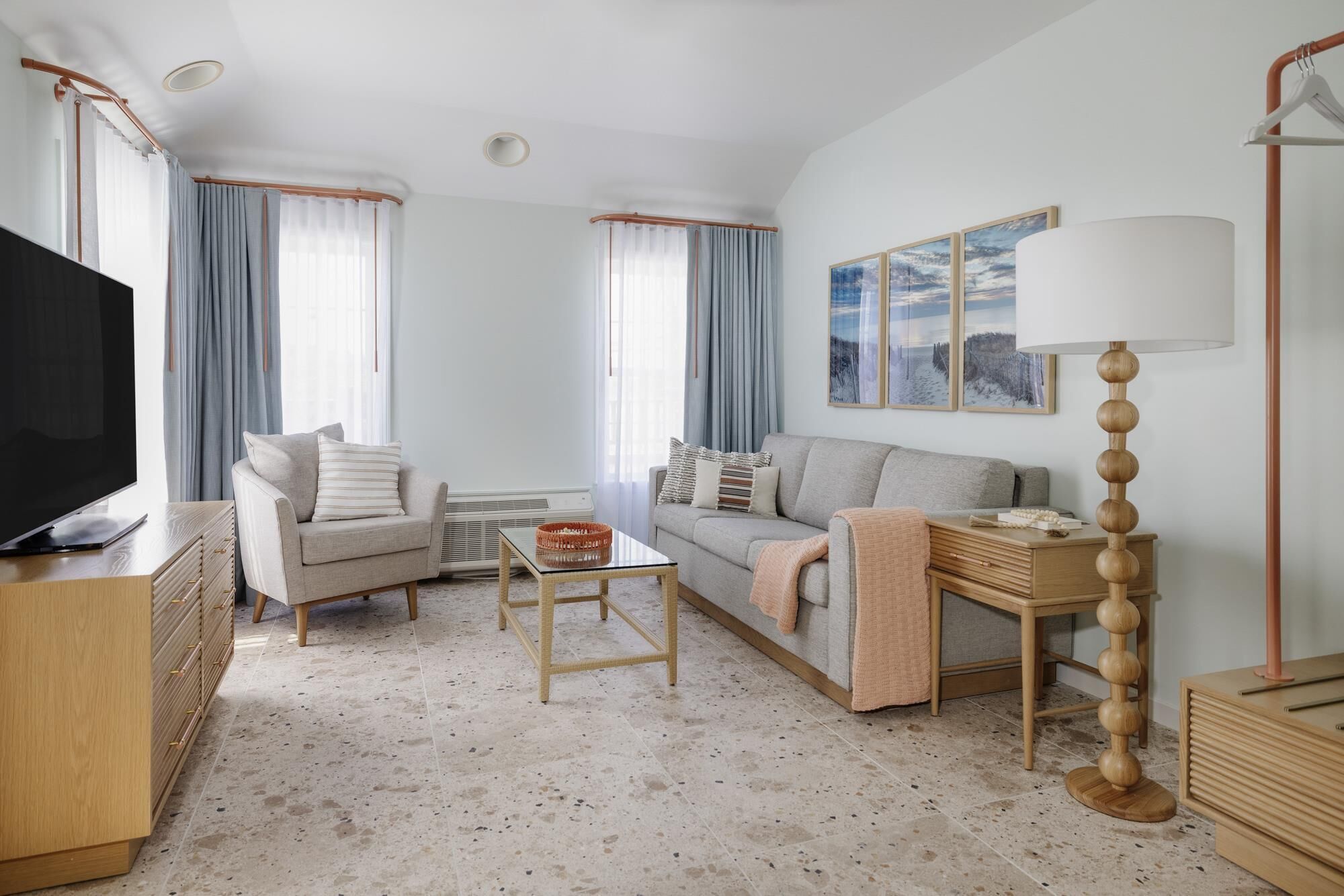 Una sala de estar moderna con un sofá, sillones, una mesa de centro, un televisor y una lámpara.