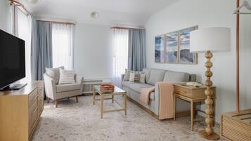 Una sala de estar moderna con un sofá, sillones, una mesa de centro, un televisor y una lámpara.