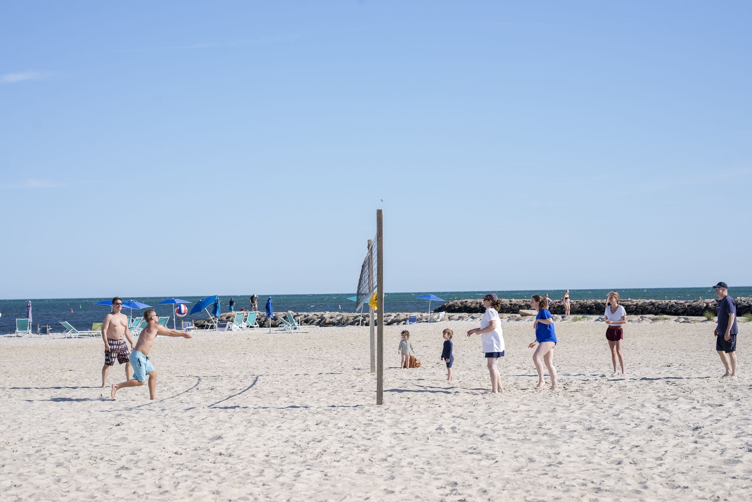 A beach volleyball game with players and spectators.