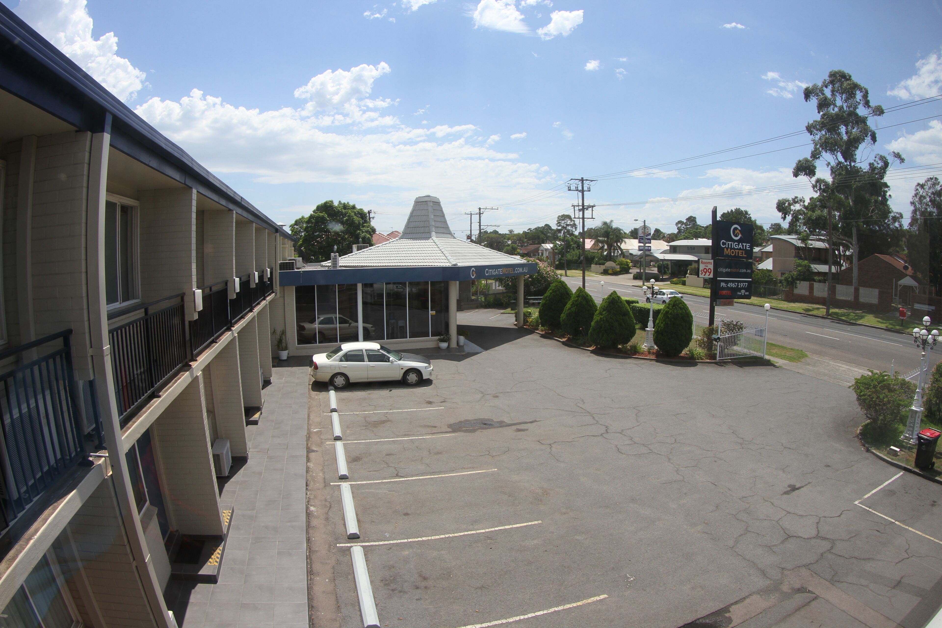 A hotel with a parking lot, a covered entrance, and a view of the street.