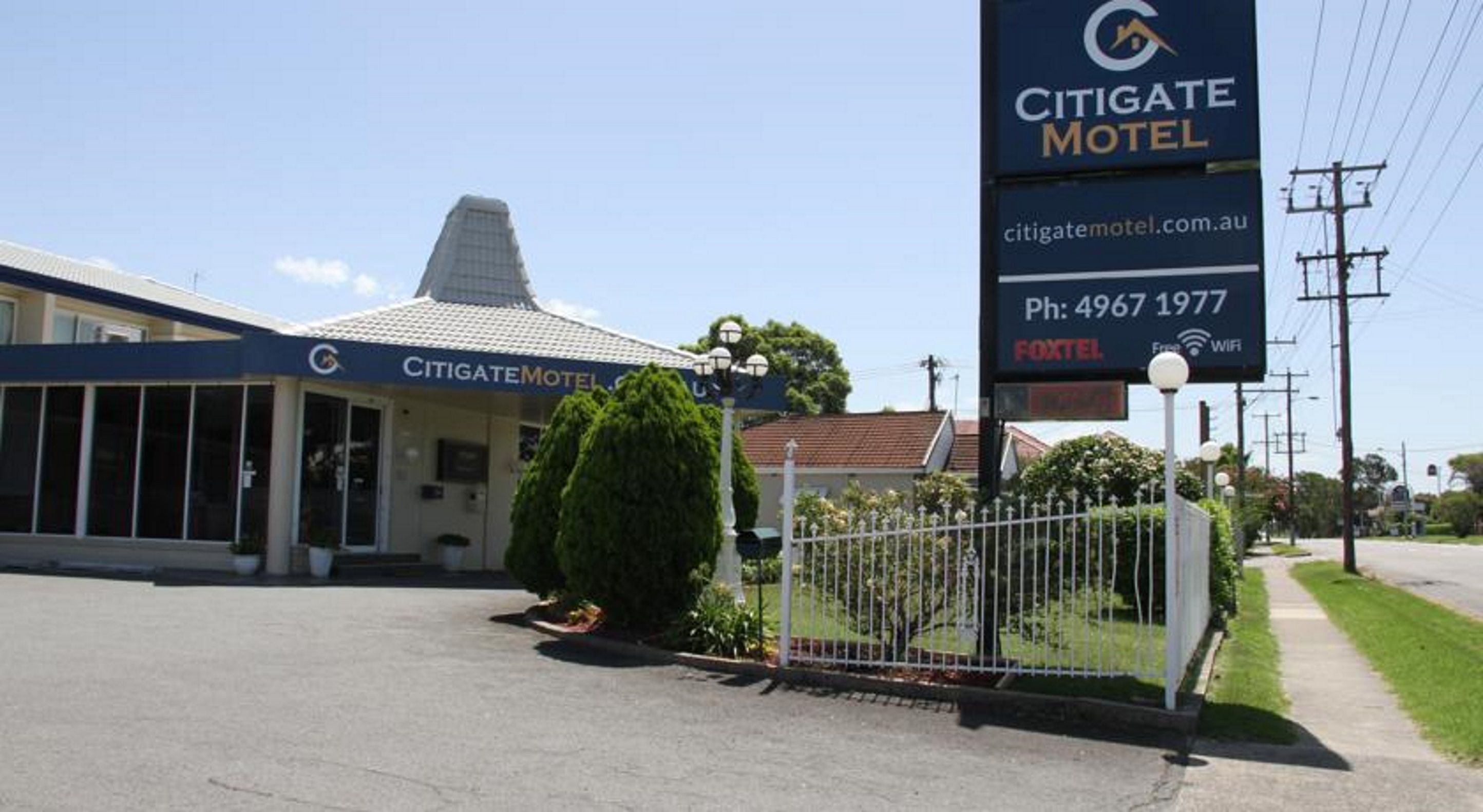 Un motel con un letrero grande, una entrada cercada y un edificio de techo inclinado.