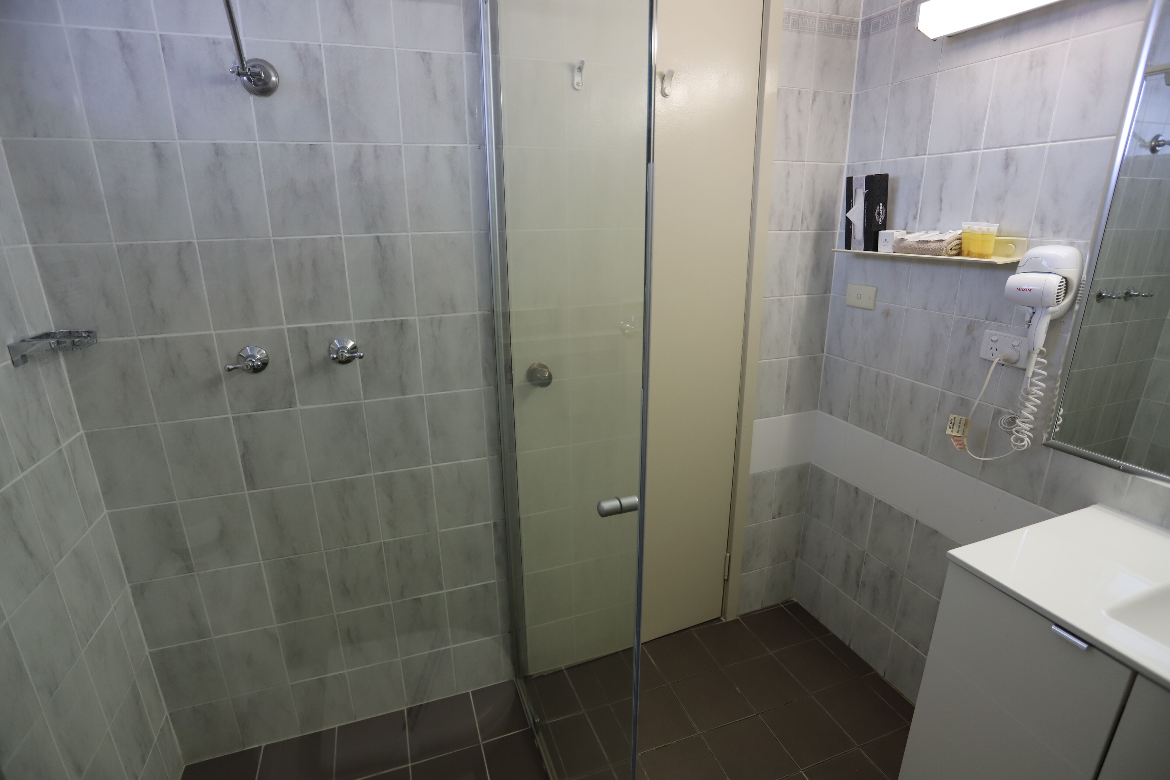 A bathroom with a glass-enclosed shower, a white sink, and a mirror above the sink.