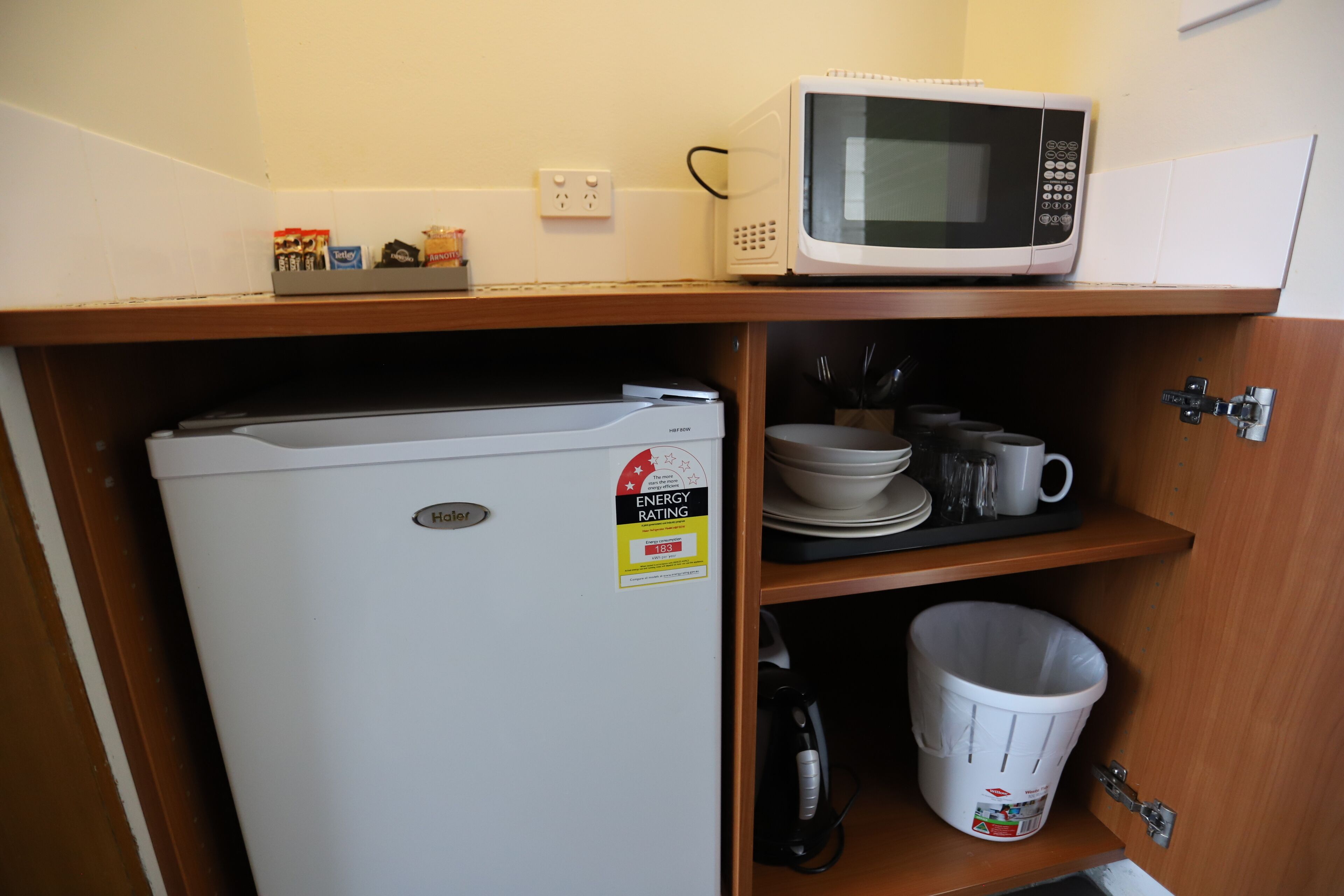 A kitchen with a white refrigerator, a microwave on the countertop, and a sink area.