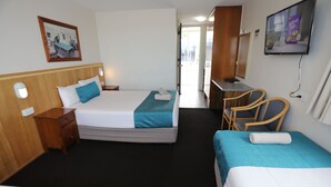 Ett hotellrum med två sängar, ett skrivbord, en stol, en tv och en tavla på väggen.
