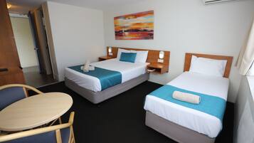 A hotel room with two beds, a small table, and a chair.