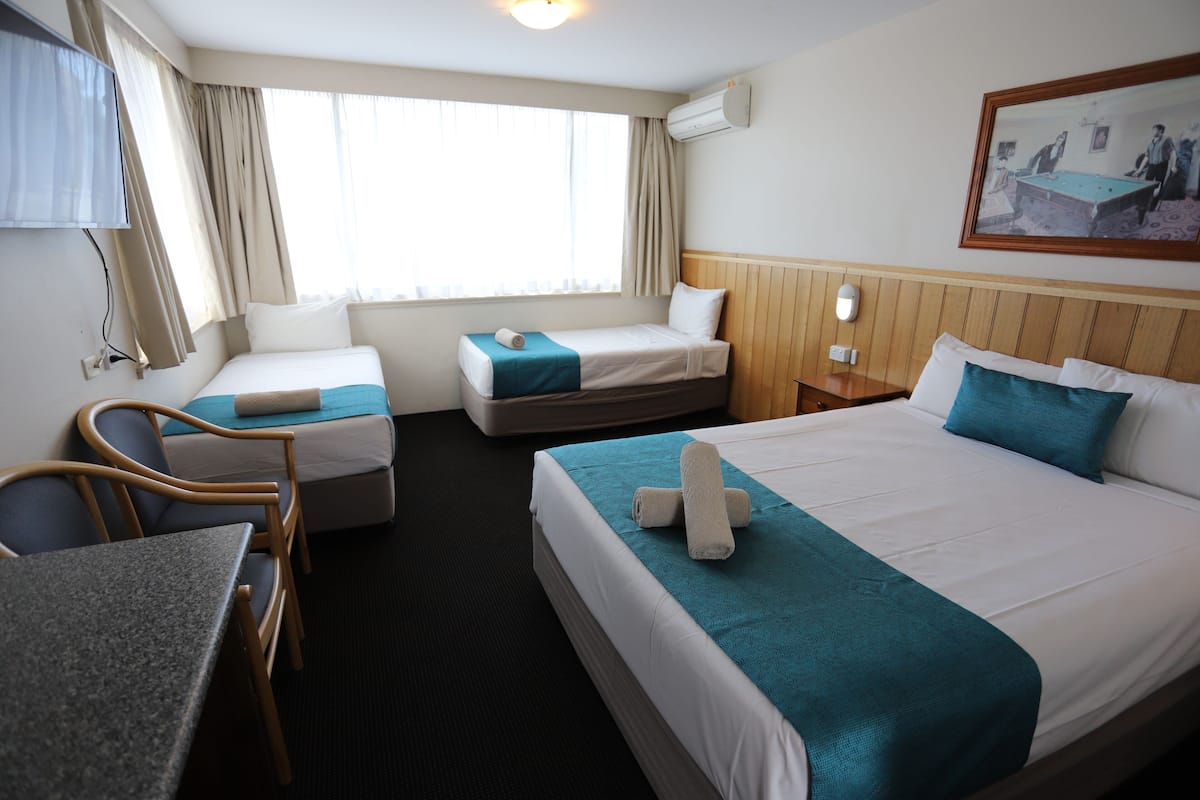 A hotel room with two single beds, a desk, and a chair.